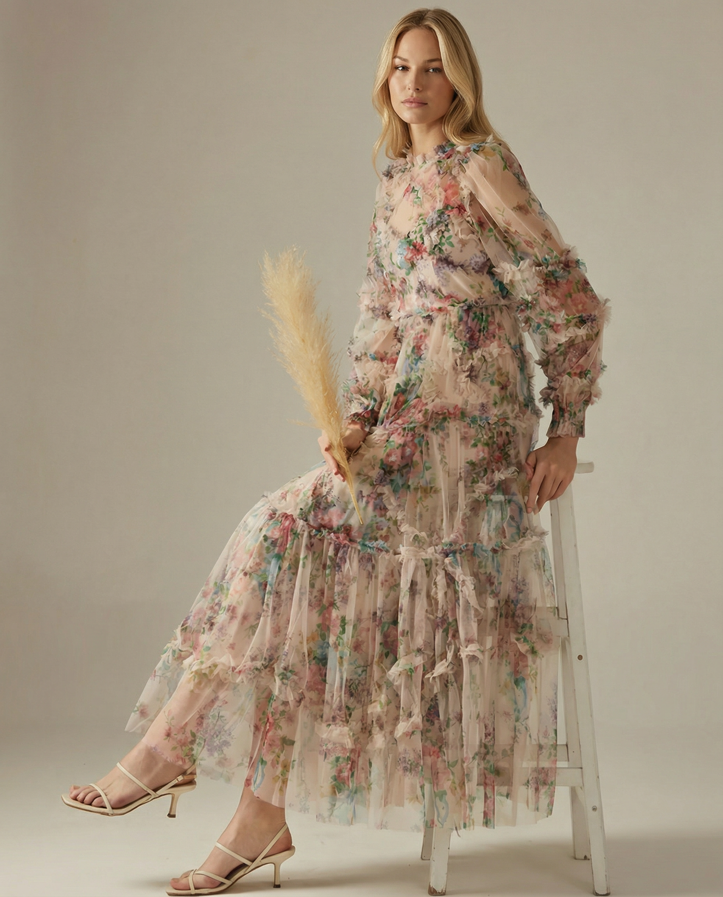 Apricot - A model wearing a high-neck, long-sleeved maxi dress in black tulle with a vibrant multi-coloured floral print, featuring tiered ruffles and sheer sleeves.