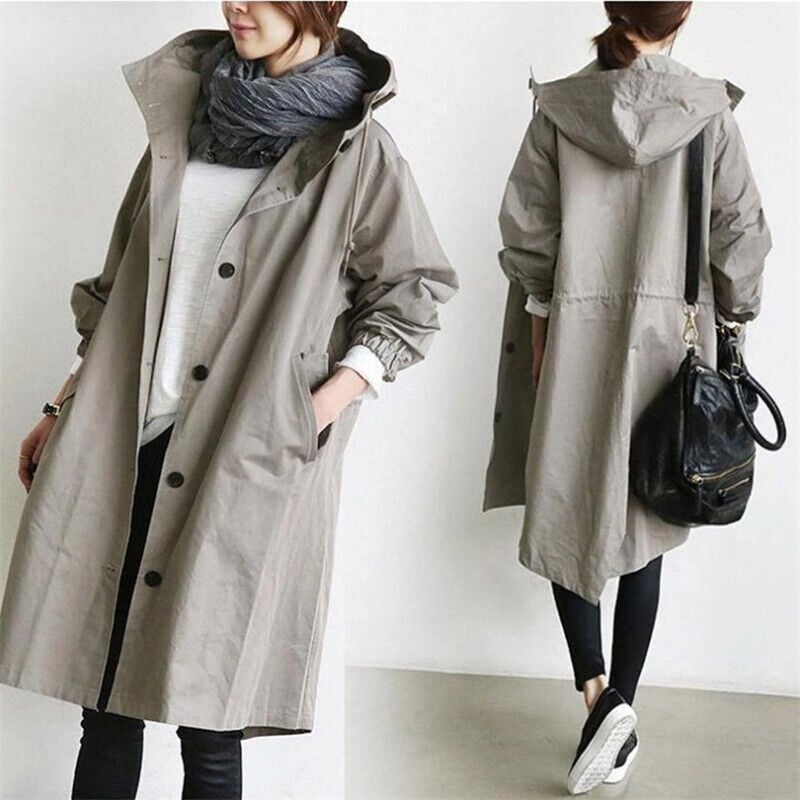 Grey 2 - A model wearing a light grey mid-length hooded coat with a single-breasted button front, styled with a black scarf and black pants against a plain white background.