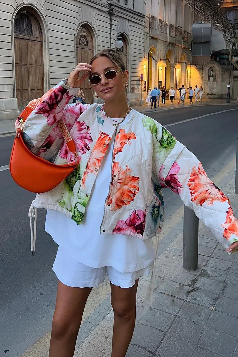Women's oversized, cropped quilted jacket featuring a bold, large-scale floral print on a light background, styled with a snap-button front and drawstring hem.