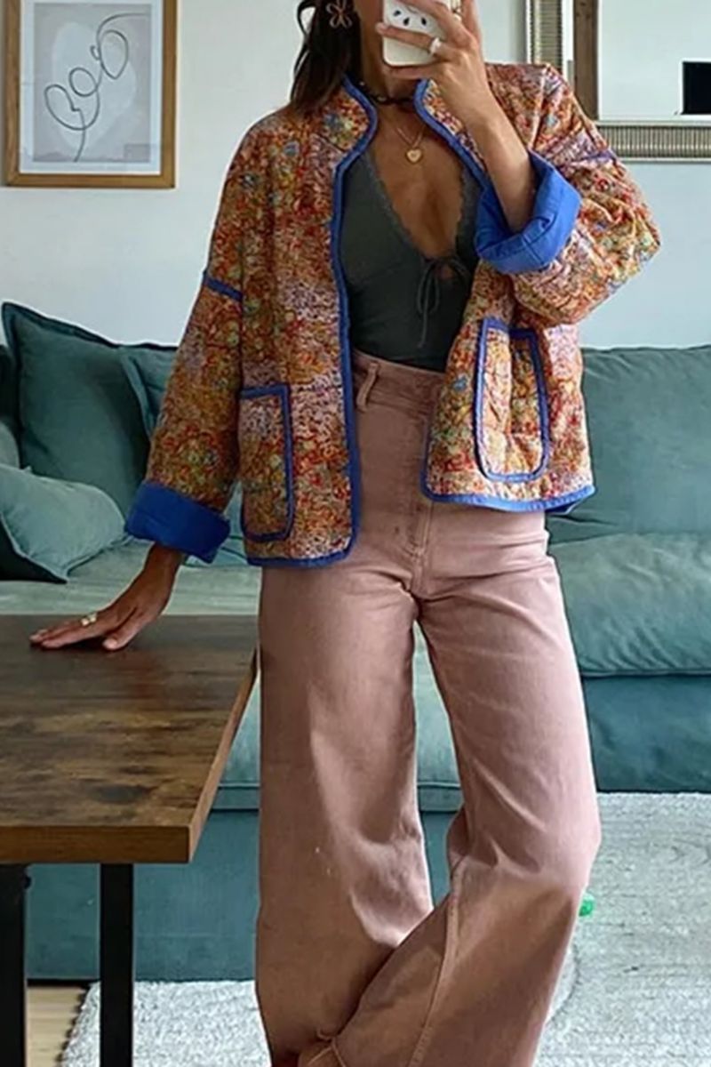 Women's relaxed-fit quilted jacket featuring a vibrant floral print, contrast blue binding on the edges and cuffs, and front patch pockets, worn open.