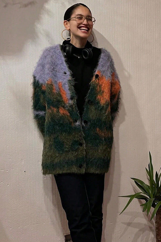 Multi - Woman wearing an oversized, fluffy knit cardigan featuring an abstract landscape pattern in shades of green, purple, and orange over a black turtleneck.