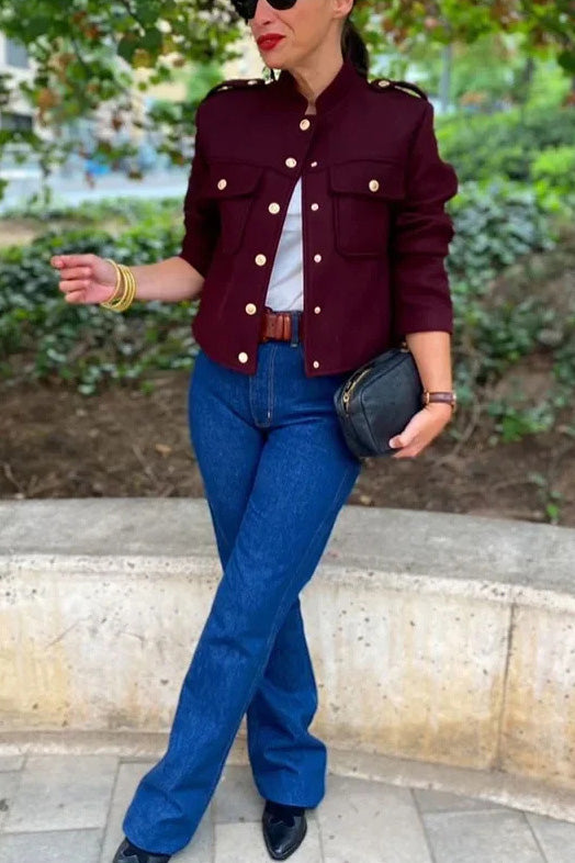 Wine Red - A woman wearing a deep burgundy, military-inspired cropped jacket with gold-tone buttons and chest pockets, paired with grey trousers.