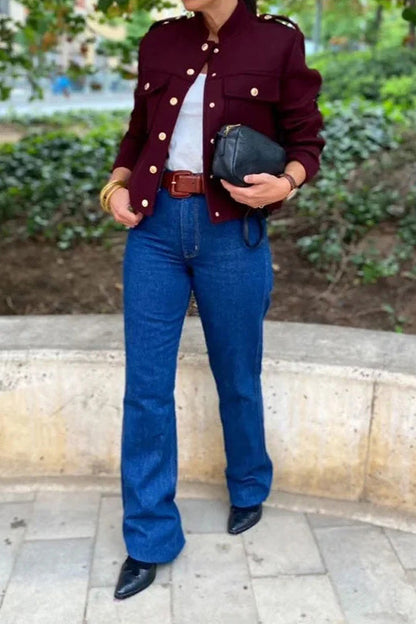 Wine Red - A woman wearing a deep burgundy, military-inspired cropped jacket with gold-tone buttons and chest pockets, paired with grey trousers.
