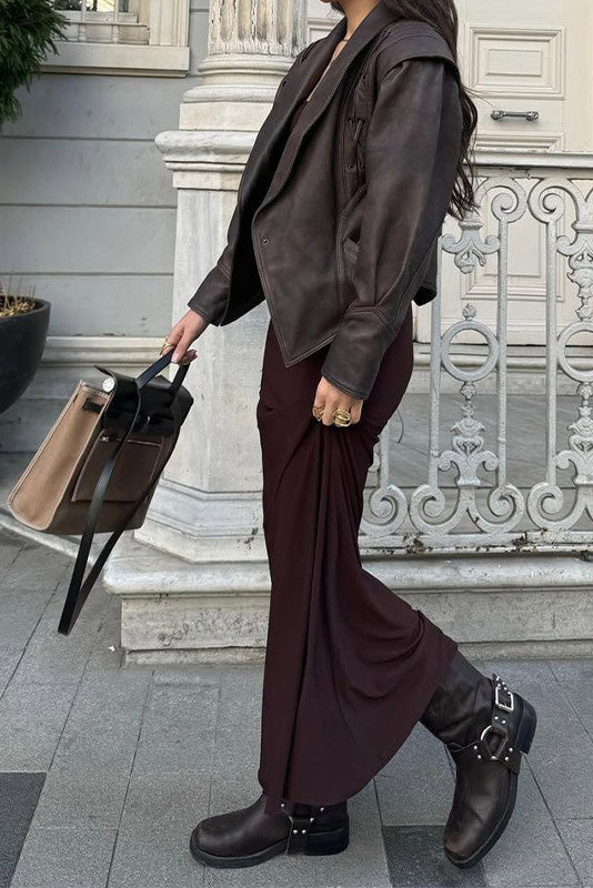 Wine Red - A woman wearing a dark brown, structured wrap faux leather jacket with a tie waist, pronounced shoulders with lace-up details, and a pointed peplum hem.