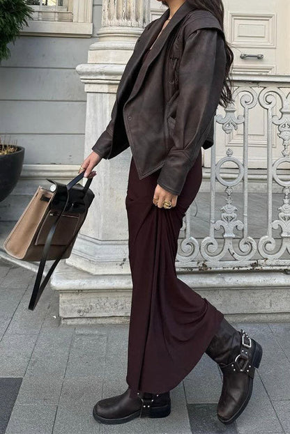 Wine Red - A woman wearing a dark brown, structured wrap faux leather jacket with a tie waist, pronounced shoulders with lace-up details, and a pointed peplum hem.