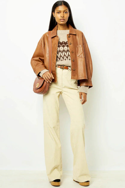 Brown - A woman wearing a relaxed-fit, brown faux leather button-front jacket with a classic collar and single chest pocket, styled over a patterned knit sweater.