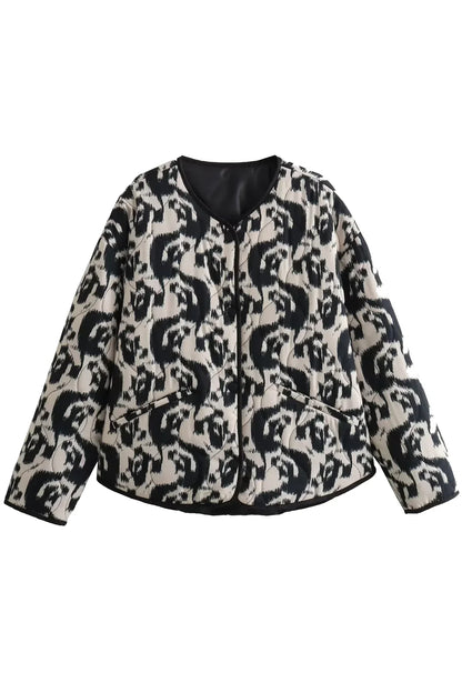 Black - Woman wearing a smart casual quilted collarless jacket with an abstract black and white print, layered over a white top and black bottoms.
