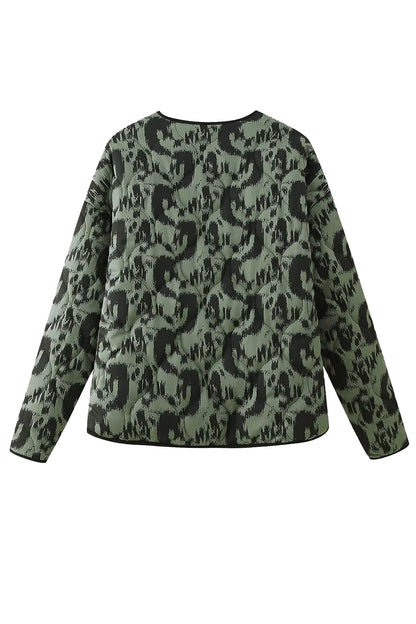 Green - Woman wearing a smart casual quilted collarless jacket with an abstract black and white print, layered over a white top and black bottoms.