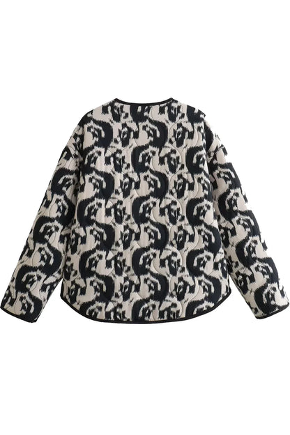 Black - Woman wearing a smart casual quilted collarless jacket with an abstract black and white print, layered over a white top and black bottoms.