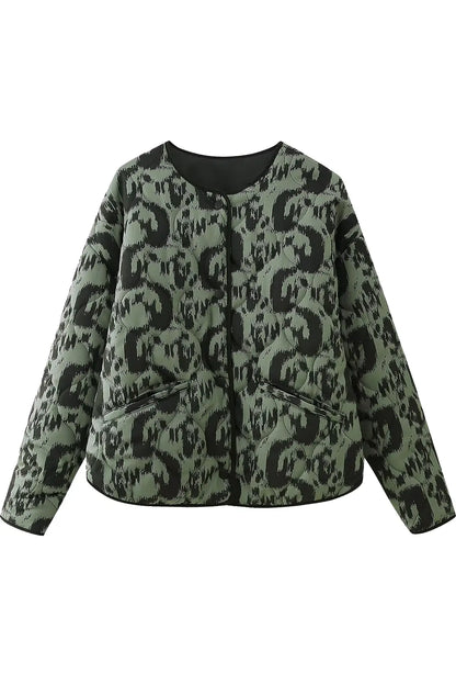 Green - Woman wearing a smart casual quilted collarless jacket with an abstract black and white print, layered over a white top and black bottoms.