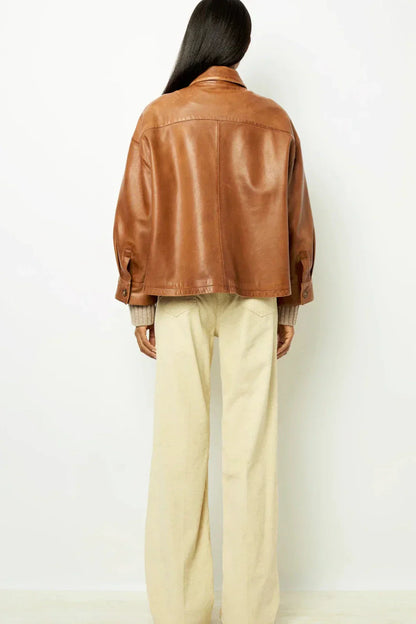 Brown - A woman wearing a relaxed-fit, brown faux leather button-front jacket with a classic collar and single chest pocket, styled over a patterned knit sweater.