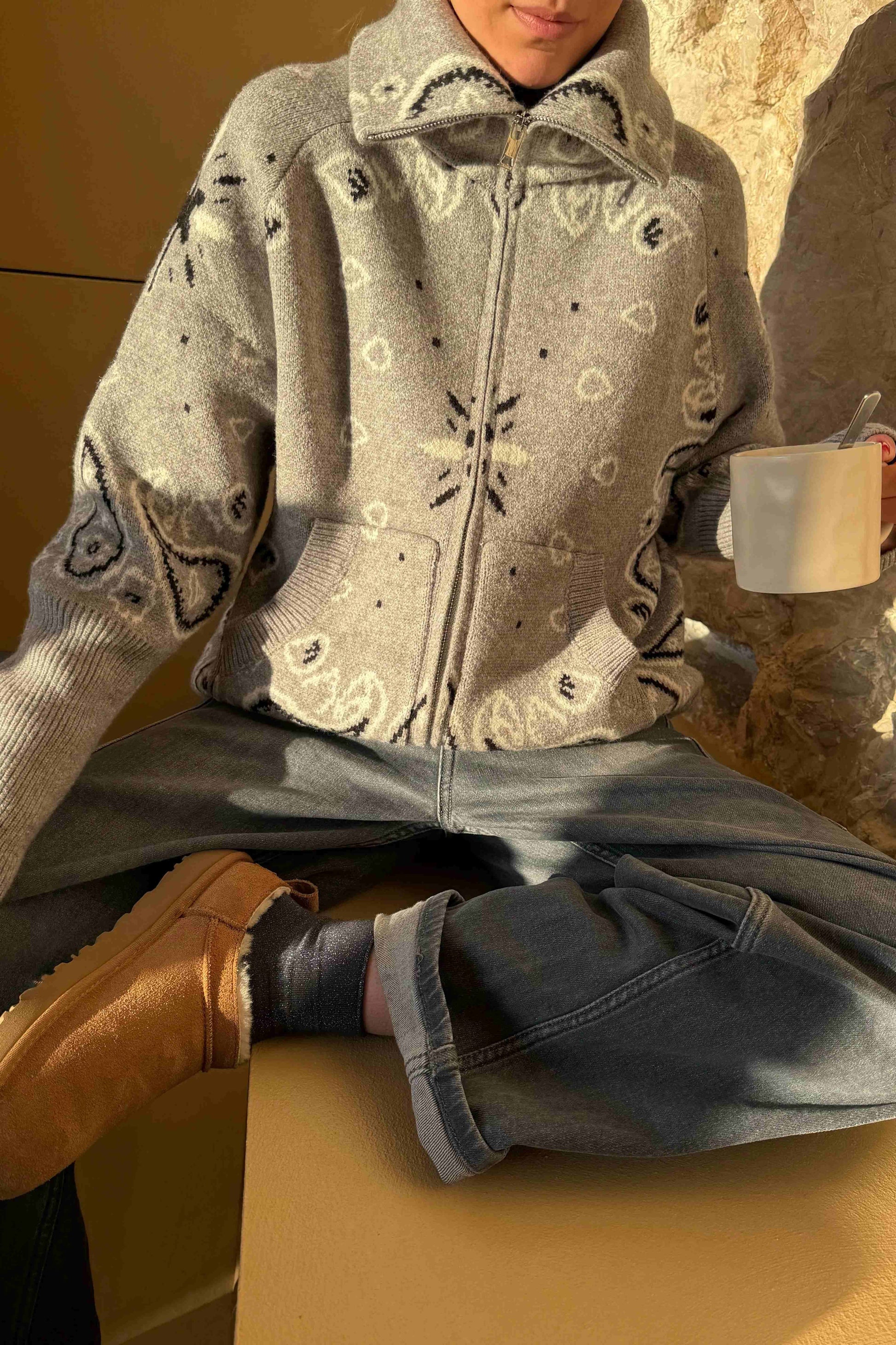 Grey - Woman taking a mirror selfie wearing a grey zip-up knit sweater with a black and white bandana pattern, featuring a high funnel neck and front pockets.