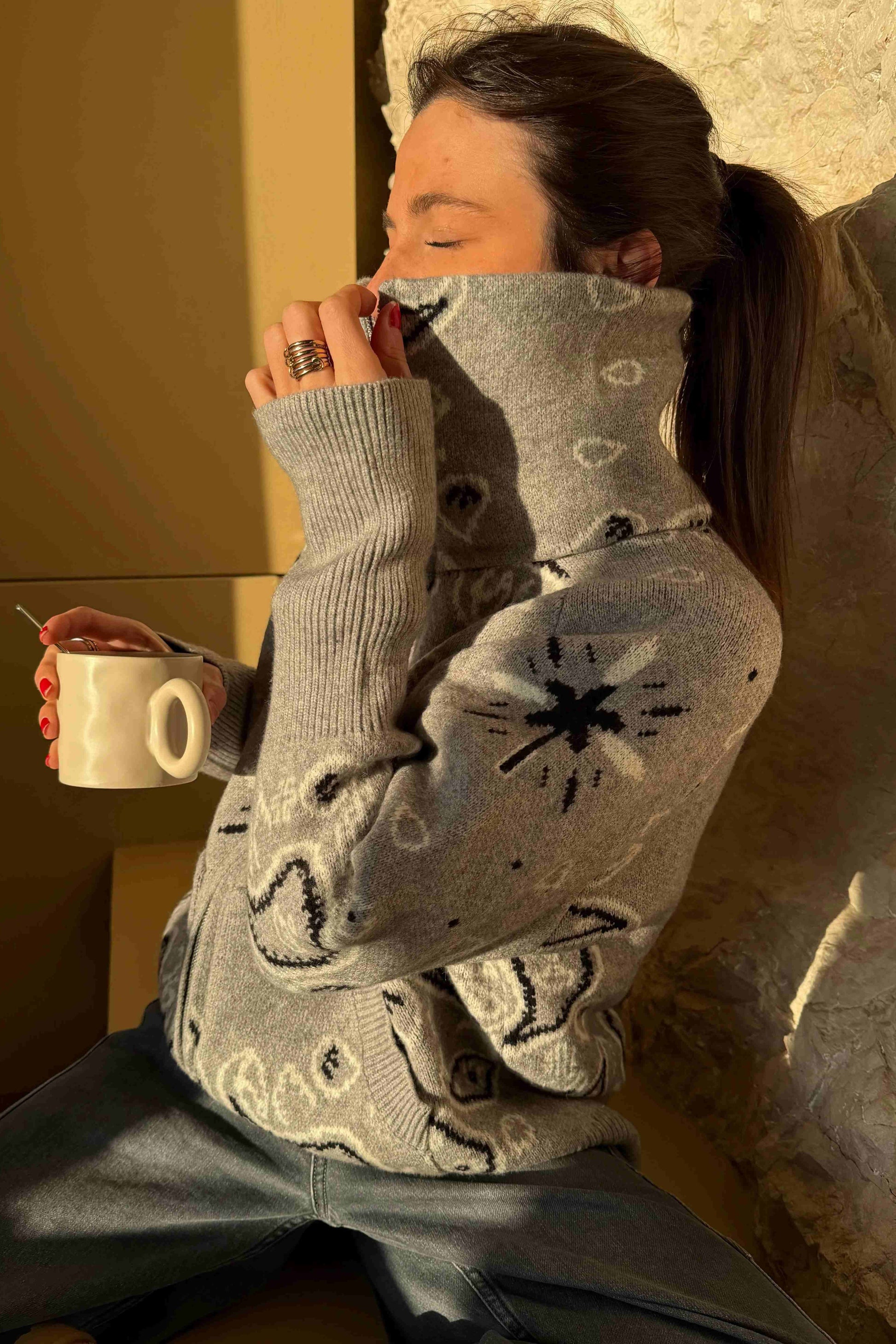 Grey - Woman taking a mirror selfie wearing a grey zip-up knit sweater with a black and white bandana pattern, featuring a high funnel neck and front pockets.
