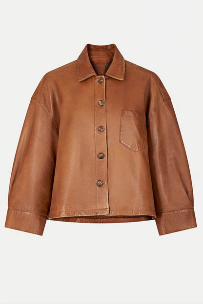 Brown - A woman wearing a relaxed-fit, brown faux leather button-front jacket with a classic collar and single chest pocket, styled over a patterned knit sweater.