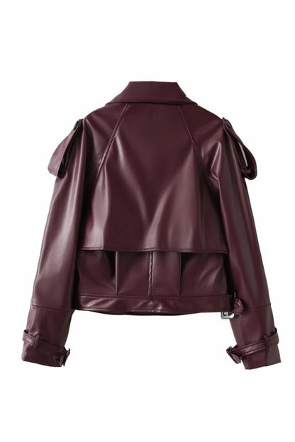 Red - Woman wearing an oversized burgundy faux leather moto jacket with exaggerated shoulders, wide collar, and belted cuffs, styled in a chic city setting.