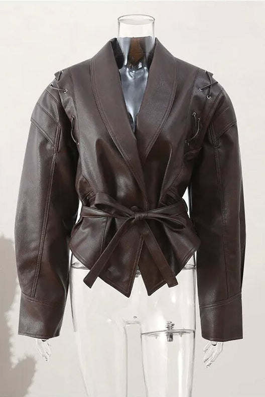 Wine Red - A woman wearing a dark brown, structured wrap faux leather jacket with a tie waist, pronounced shoulders with lace-up details, and a pointed peplum hem.