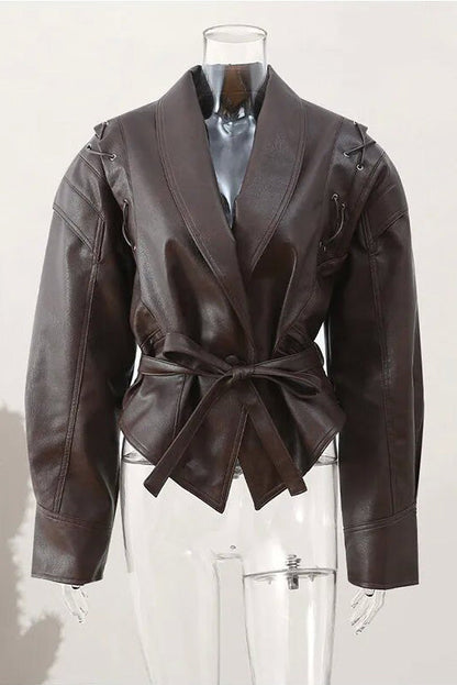 Wine Red - A woman wearing a dark brown, structured wrap faux leather jacket with a tie waist, pronounced shoulders with lace-up details, and a pointed peplum hem.