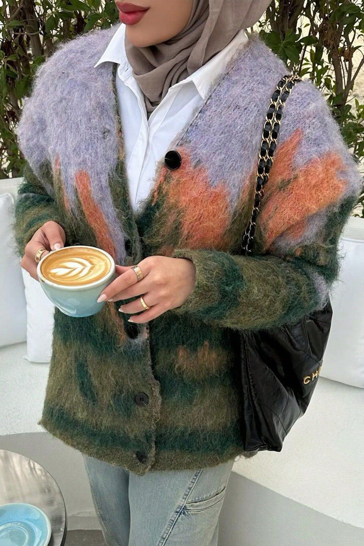 Multi - Woman wearing an oversized, fluffy knit cardigan featuring an abstract landscape pattern in shades of green, purple, and orange over a black turtleneck.