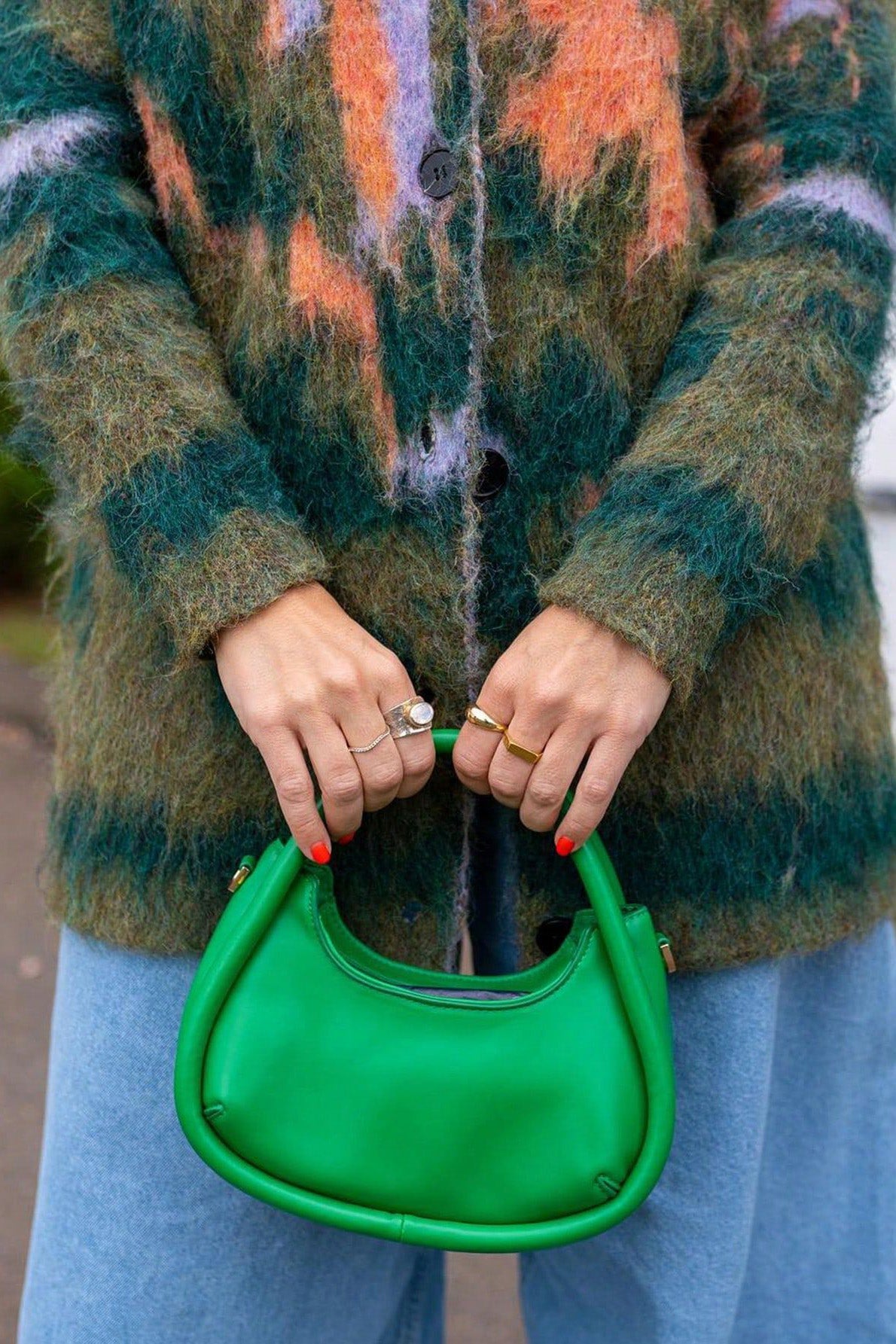 Multi - Woman wearing an oversized, fluffy knit cardigan featuring an abstract landscape pattern in shades of green, purple, and orange over a black turtleneck.