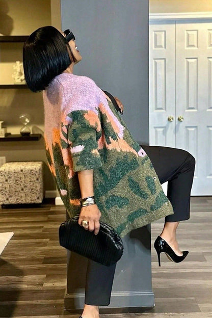 Multi - Woman wearing an oversized, fluffy knit cardigan featuring an abstract landscape pattern in shades of green, purple, and orange over a black turtleneck.