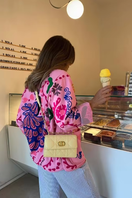 Women's pink long-sleeve relaxed-fit jacket featuring vibrant multi-coloured floral and geometric embroidery, a V-neckline, large contrasting buttons, and front patch pockets.
