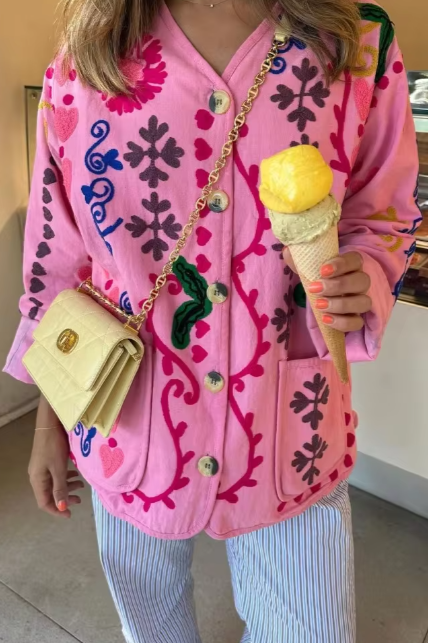 Women's pink long-sleeve relaxed-fit jacket featuring vibrant multi-coloured floral and geometric embroidery, a V-neckline, large contrasting buttons, and front patch pockets.