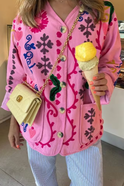 Women's pink long-sleeve relaxed-fit jacket featuring vibrant multi-coloured floral and geometric embroidery, a V-neckline, large contrasting buttons, and front patch pockets.