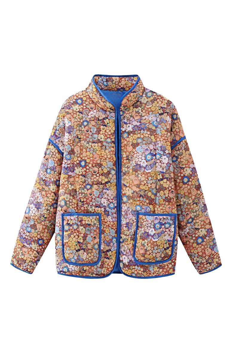 Women's relaxed-fit quilted jacket featuring a vibrant floral print, contrast blue binding on the edges and cuffs, and front patch pockets, worn open.