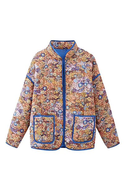Women's relaxed-fit quilted jacket featuring a vibrant floral print, contrast blue binding on the edges and cuffs, and front patch pockets, worn open.