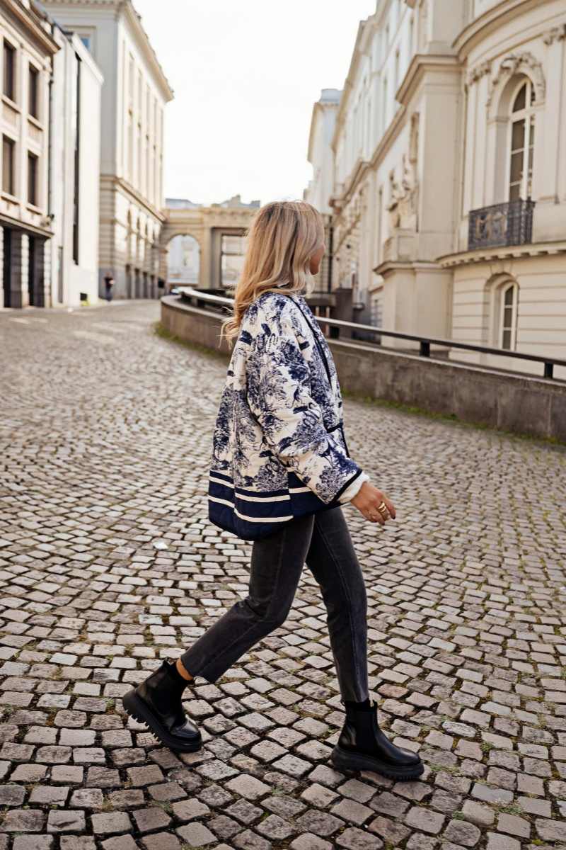 Women's oversized quilted jacket featuring a navy and white toile scenic print, open front, and contrast striped borders on the wide sleeves and hem.