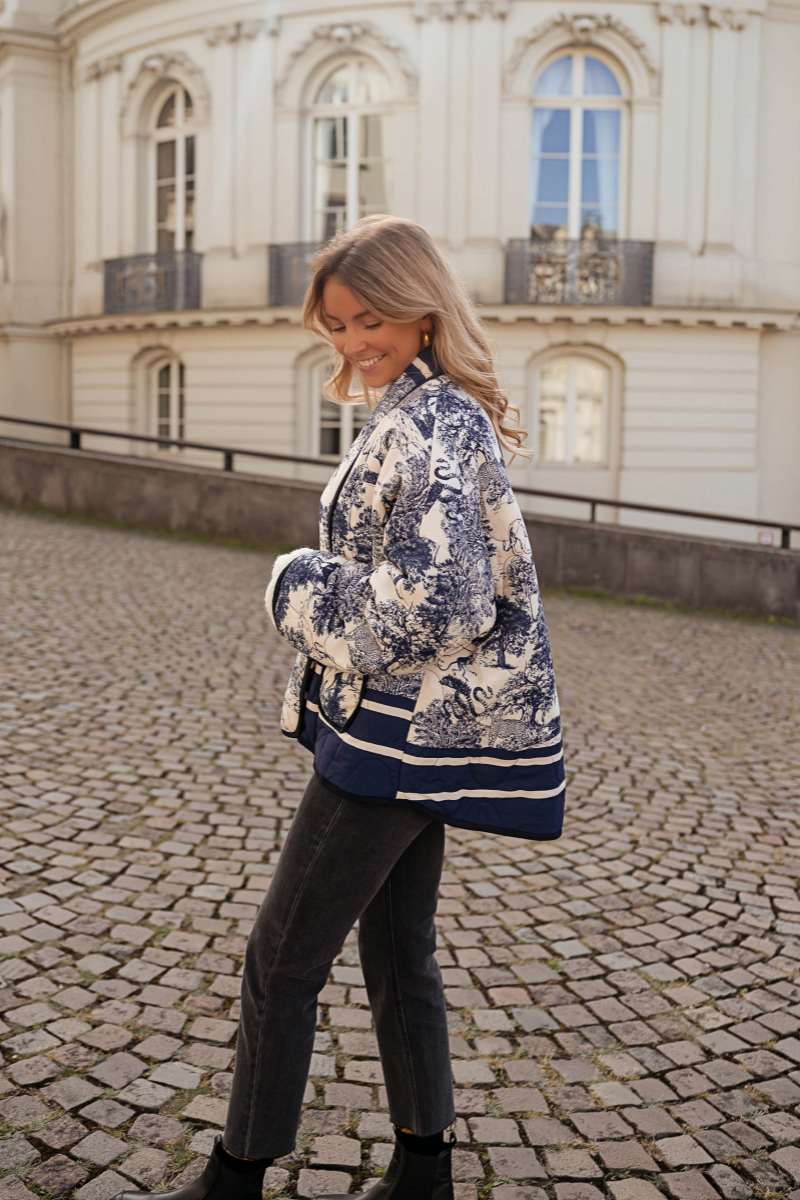 Women's oversized quilted jacket featuring a navy and white toile scenic print, open front, and contrast striped borders on the wide sleeves and hem.