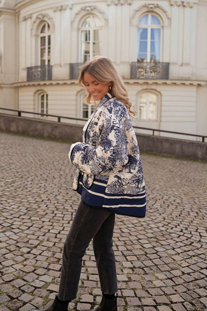 Women's oversized quilted jacket featuring a navy and white toile scenic print, open front, and contrast striped borders on the wide sleeves and hem.