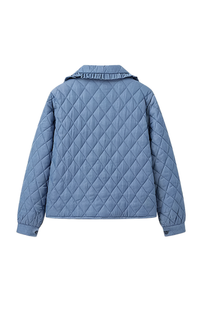 Women's blue diamond-quilted denim jacket featuring a ruffled collar, tie-front closure, and voluminous balloon sleeves, styled with distressed shorts and cowboy boots.