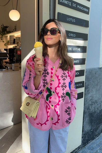 Women's pink long-sleeve relaxed-fit jacket featuring vibrant multi-coloured floral and geometric embroidery, a V-neckline, large contrasting buttons, and front patch pockets.