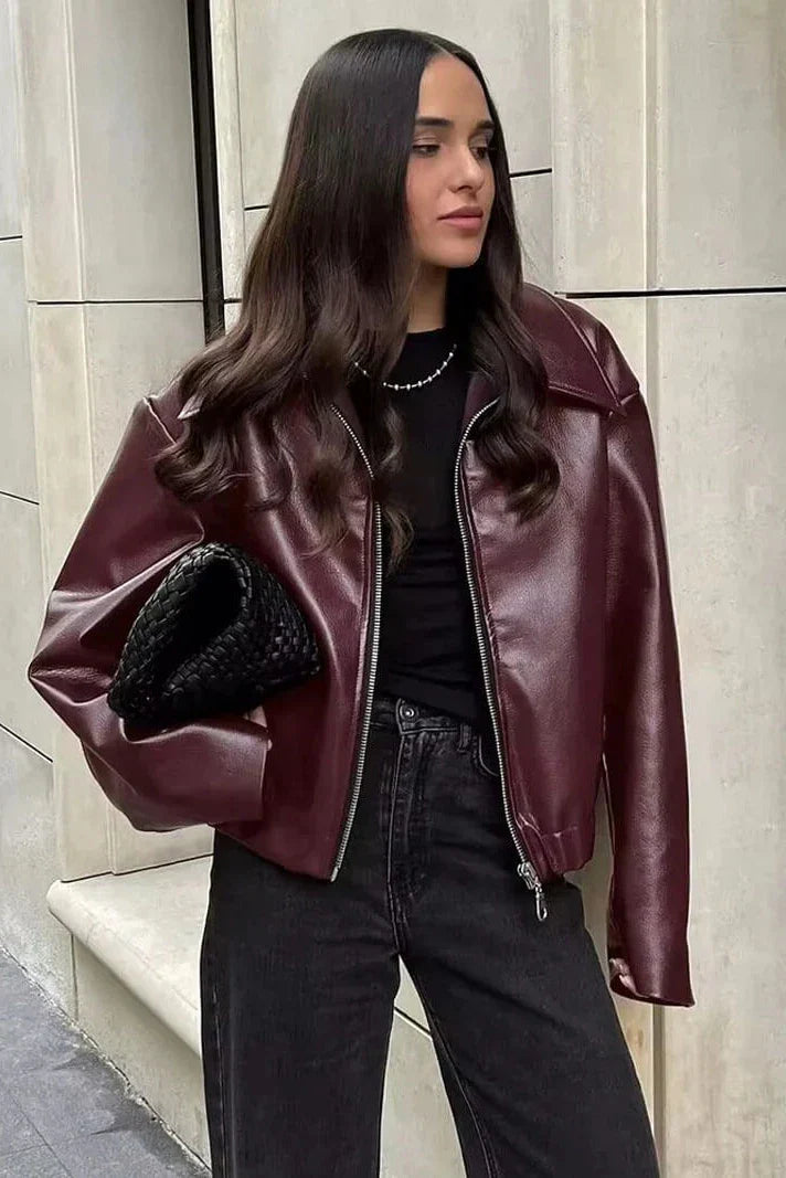 Amaranth - Women's deep burgundy faux leather zip-front cropped bomber jacket with a wide collar, styled over a black top and dark denim.