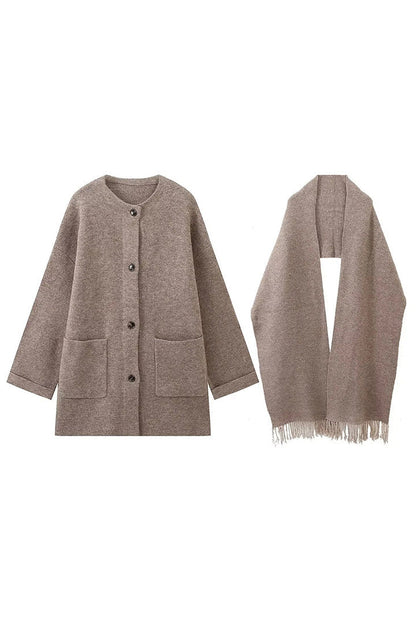 Grey - A woman wearing a taupe brushed wool mid-length coat with an integrated matching scarf, styled with dark sunglasses and a plum clutch against a classic brick building background.