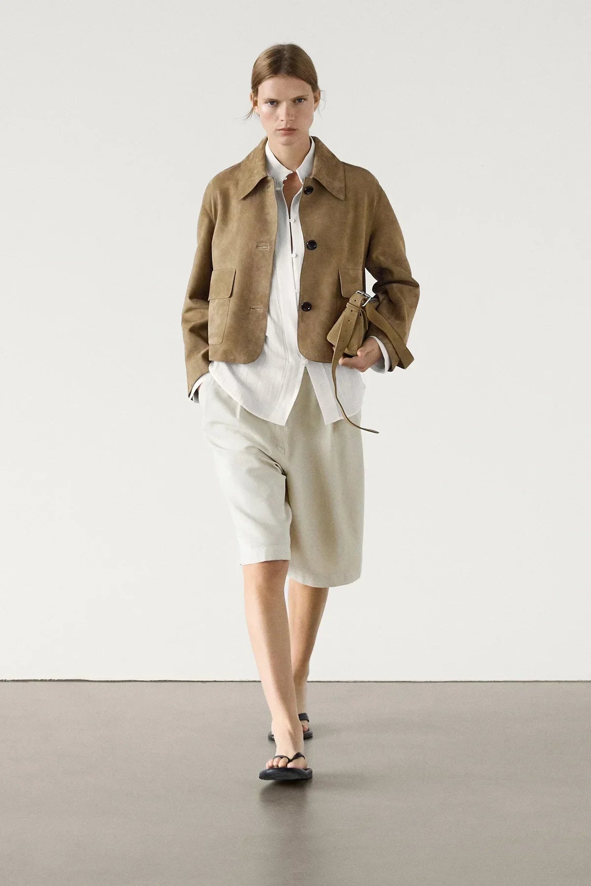 sand - Women's tan suede-look cropped jacket featuring a point collar, large button closures, and two front flap pockets, styled over white tailored shorts.
