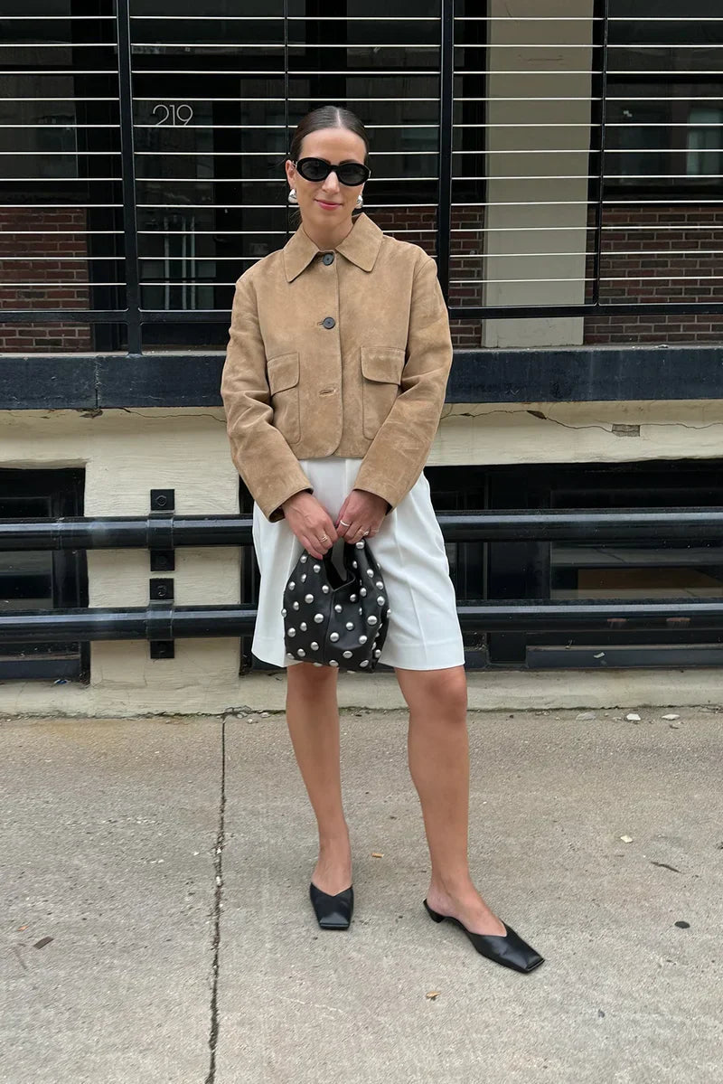 sand - Women's tan suede-look cropped jacket featuring a point collar, large button closures, and two front flap pockets, styled over white tailored shorts.