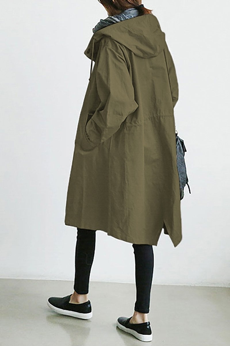 Pink - A woman wearing a teal mid-length hooded coat with a contrast black button-down front, angled flap pockets, and elasticated cuffs, set against a bright minimalist interior.