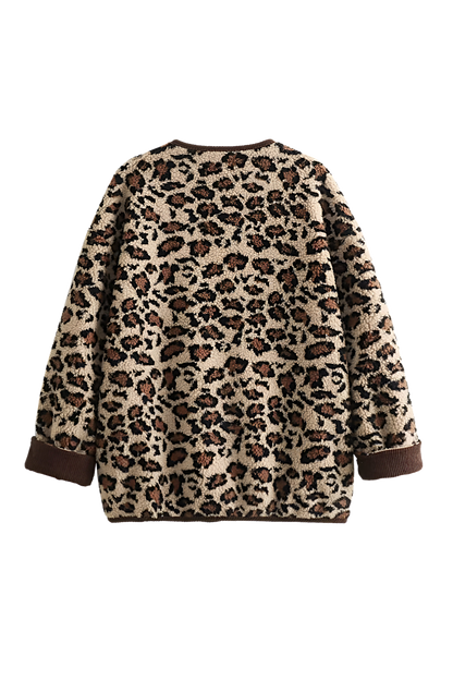A woman wearing a relaxed-fit, fuzzy knit cardigan featuring a bold leopard print and contrasting dark ribbed placket, styled open over a white top and blue jeans.