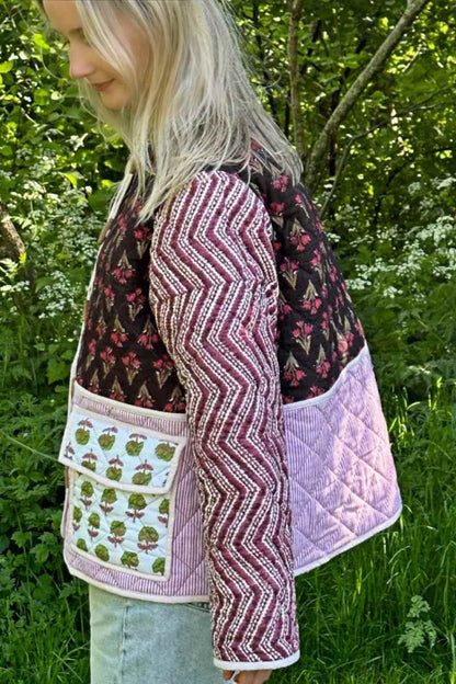 Woman wearing a quilted patchwork jacket featuring mixed floral and chevron prints, paired with a white maxi skirt.