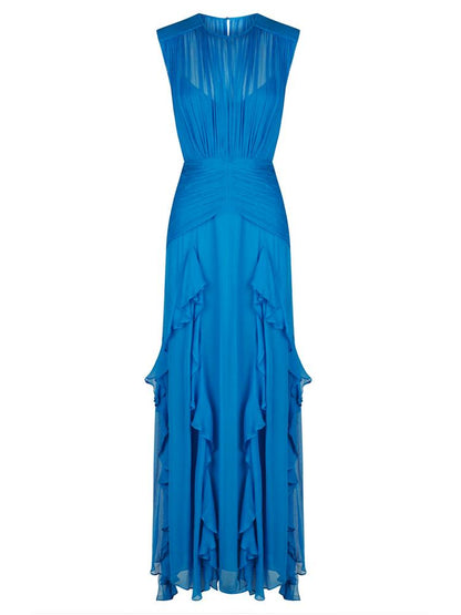 Blue - A woman wearing a vibrant cobalt blue sleeveless chiffon maxi dress featuring a high gathered neckline, a wide ruched waistband, and cascading vertical ruffles along the skirt.