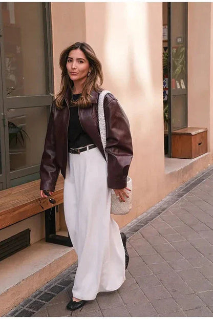 Wine Red - A woman wearing an oversized, dark brown faux leather bomber jacket with a classic collar, styled over a black top and white midi skirt for a smart casual look.