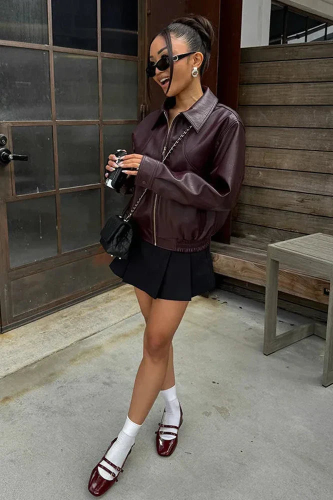 Wine Red - A woman wearing an oversized, dark brown faux leather bomber jacket with a classic collar, styled over a black top and white midi skirt for a smart casual look.