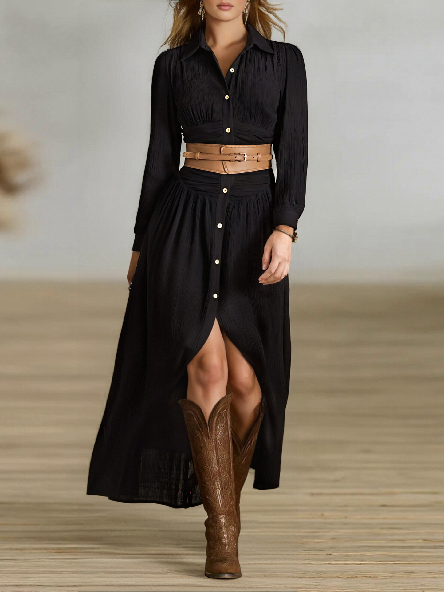 Black - A woman wearing a black, long-sleeved, crinkle-textured maxi shirt dress with a button-down front, styled with a tan leather waist belt and brown embroidered cowboy boots.
