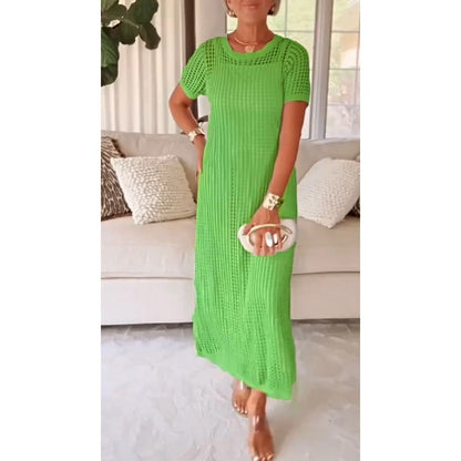 Green - A woman wearing a lavender open-knit crochet maxi dress with a crew neck and short sleeves, styled with a beige woven handbag and gold accessories.