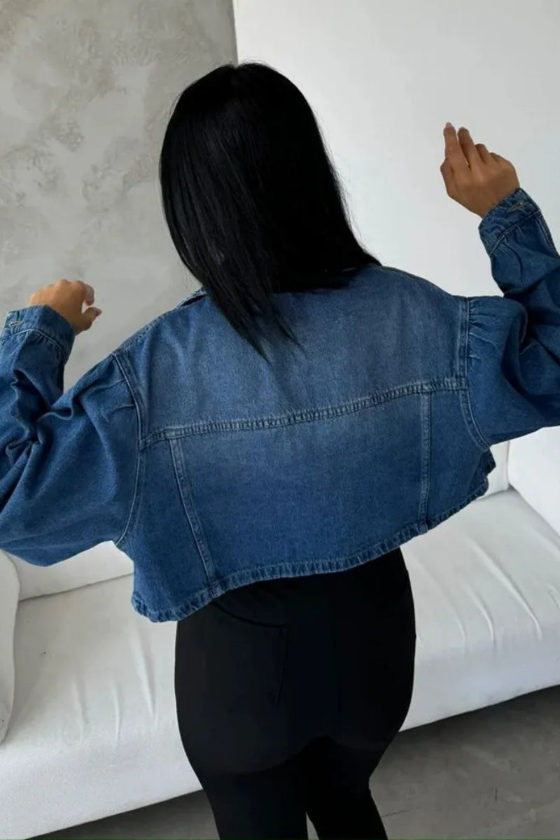 Blue - Women's cropped denim jacket featuring voluminous puff sleeves, a classic collar, and a faded wash, styled open over a black top and high-waisted pants.