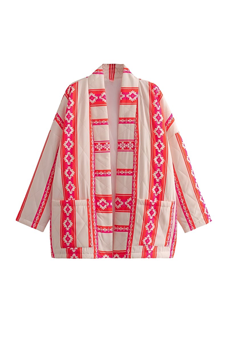 A woman wearing a relaxed, open-front kimono jacket featuring a vibrant pink and orange geometric Aztec print over a cream base, styled over a crochet crop top and shorts.