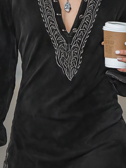 Photo Color - A model wearing a black velvet long-sleeve mini dress featuring a deep V-neckline with a collar and intricate silver-toned embroidery along the neckline, cuffs, and hem.