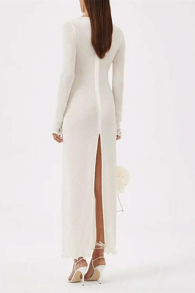 White - A woman wearing a long-sleeved, white ribbed knit maxi dress featuring a deep plunging neckline decorated with large 3D floral appliqués.